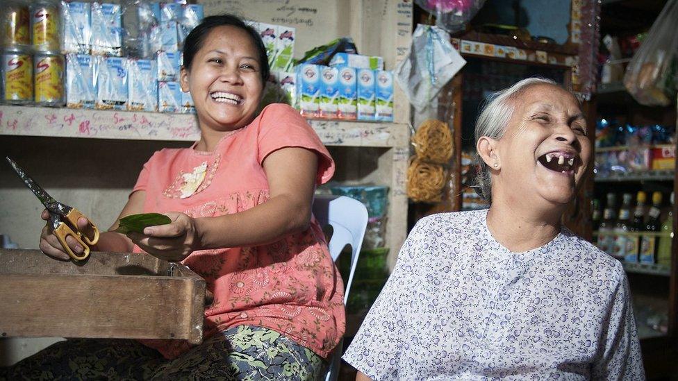 A seventy-year-old woman laughs with family members inside a grocery store in Tachilek, Myanmar. 2011