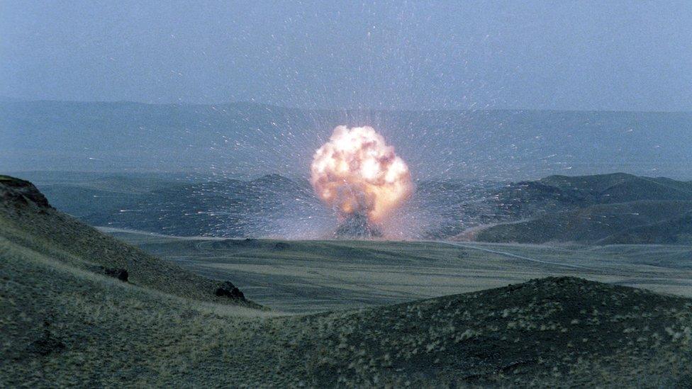 An explosion in a huge open plain of rolling green fields