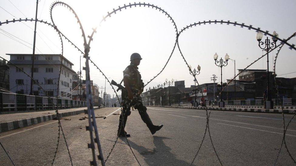 Indian military in front of barbed wire fence