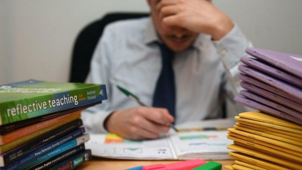 teacher at desk with head in hands