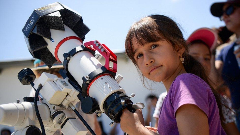 Girl stands by equipment used to view the eclipse in Neiva, Colombia.