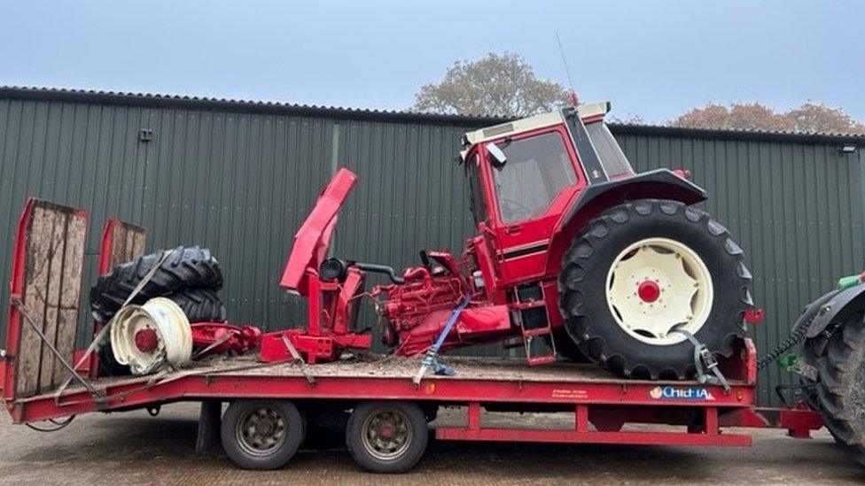 Damaged red tractor on the back of a lorry