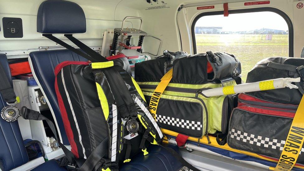 Equipment packed in bags inside a helicopter. A seat is also visible.