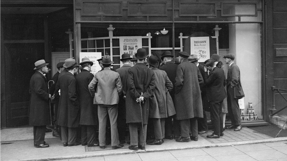 : A crowd gathers at Selfridges, London, to read about a demonstration of an early wireless machine used for sending messages