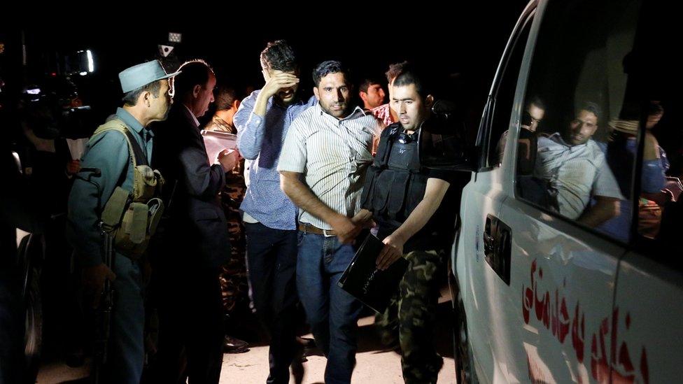 Afghan men walk towards an ambulance after they were rescued from the site of an attack at American University of Afghanistan in Kabul, Afghanistan on 24 August 2016