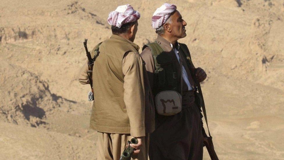 Members of the Kurdish Peshmerga forces stand with their weapons in the town of Sinjar, Iraq