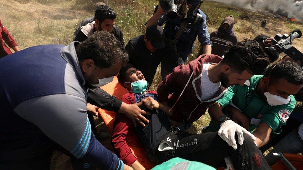 A Palestinian man is carried away after being wounded during clashes with Israeli soldiers east of Gaza City (6 April 2018)