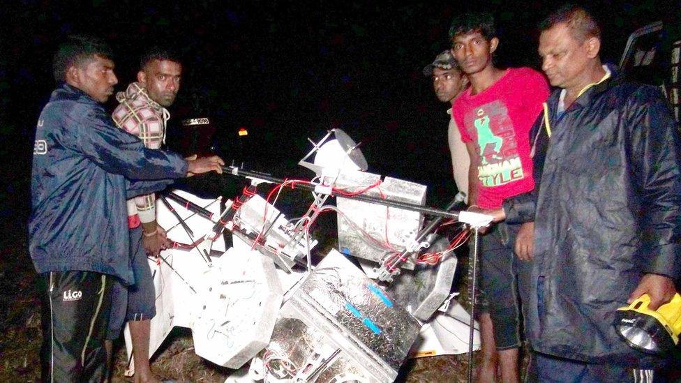 Sri Lankan men at a tea plantation look at the wreckage of a Google balloon that crashed in the central part of the country in Gampola on February 17, 2016