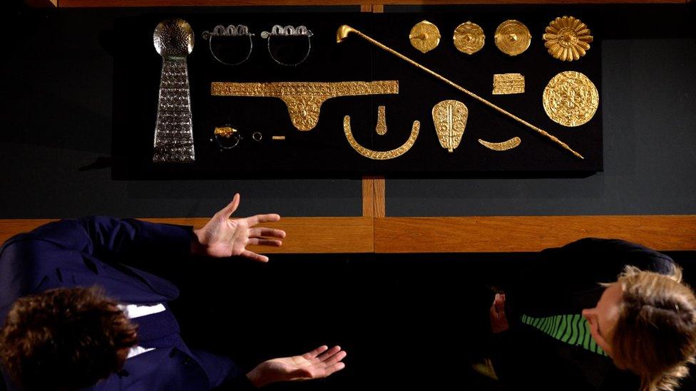 Some of the V&A's Ashanti artefacts seen from above laid out on black cloth, with museum director Tristram Hunt and the BBC's Katie Razzall