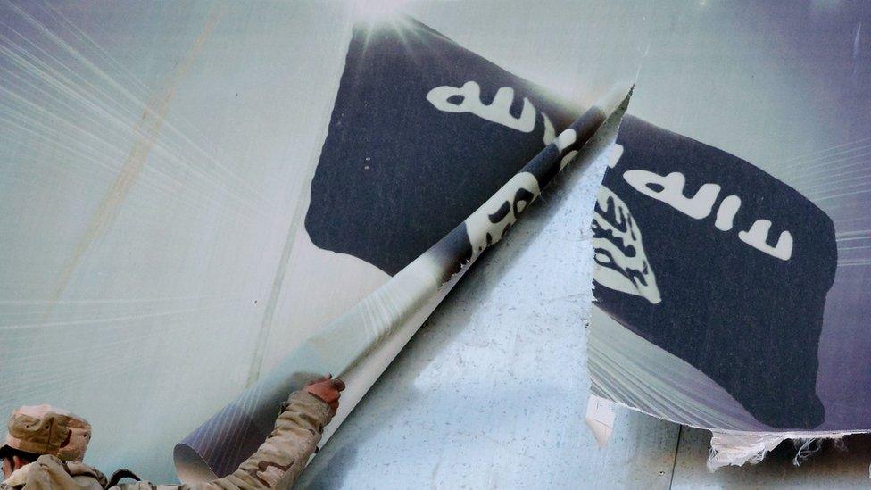 A member of the Iraqi security forces removes a banner bearing the logo of the Islamic State (IS) group in eastern Mosul on 19 January 2017