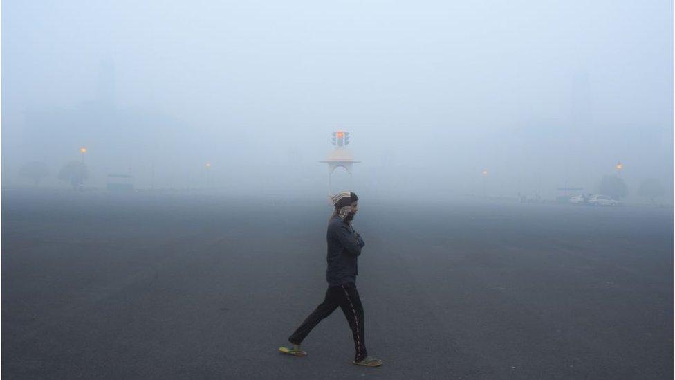 A man walking in Delhi as heavy smog shrouds buildings in the city