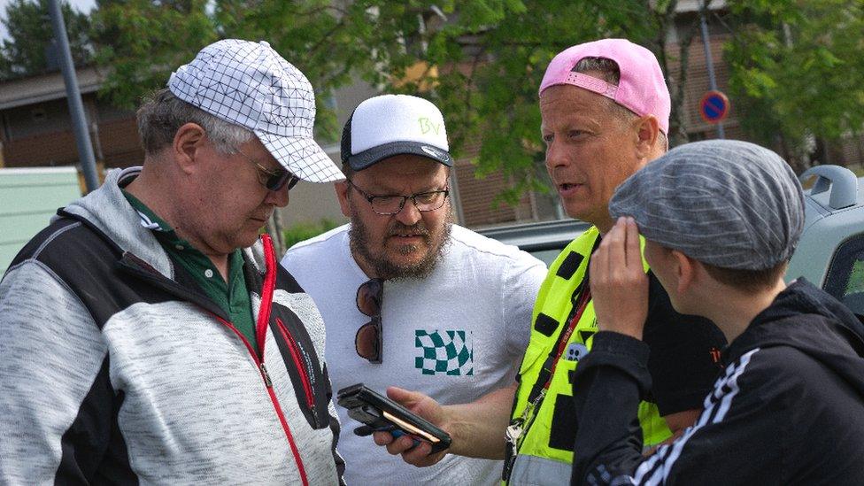 Ilkka Pulkkinen stands with three other members of his team, phone in hand chatting