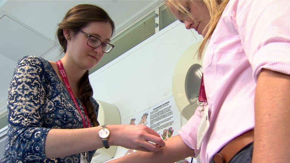 One nursing student applies a tattoo to another's arm