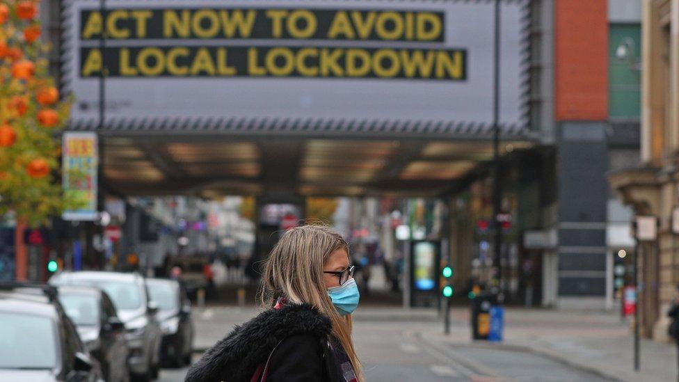 A woman wearing a mask with a Covid sign in the background