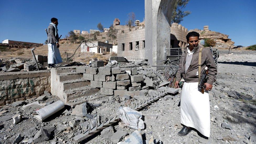 Yemeni men inspect damage caused by a reported Saudi-led coalition air strike on a rebel-controlled TV station in Sanaa (9 December 2017)