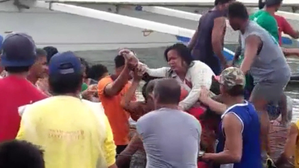 Rescuers assist people after a ferry capsized in the Philippines with 251 people on board