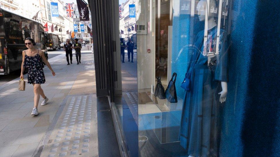 Woman walks past high-end fashion stores