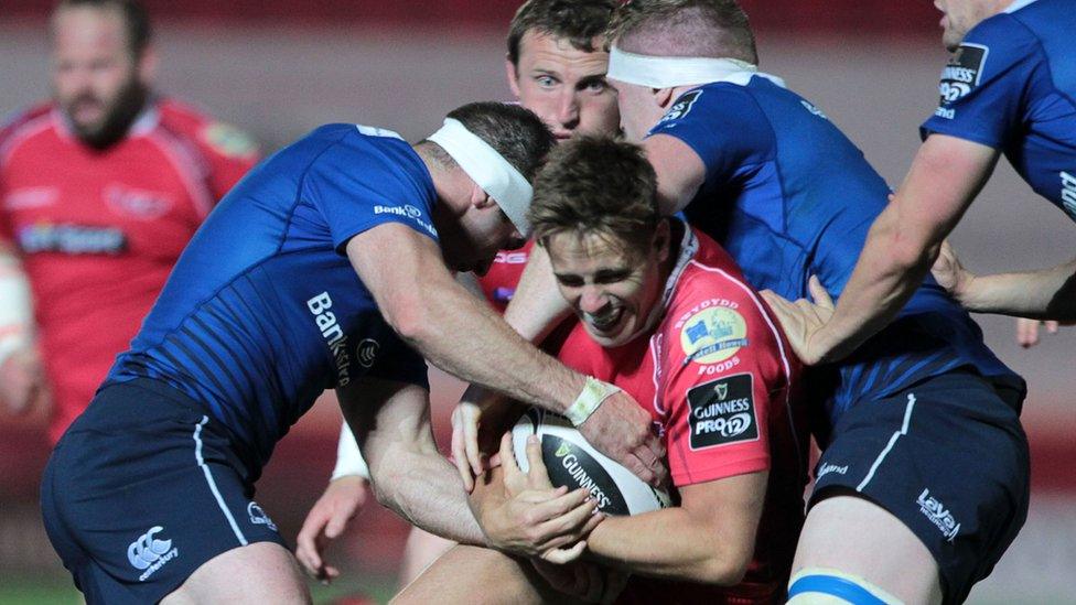 Aled Thomas of Scarlets is tackled by Fergus McFadden and Dan Leavy of Leinster