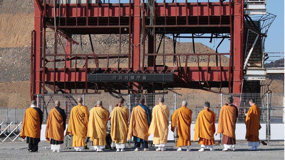 Buddhist monks pray for victims of the massive earthquake and tsunami disaster which hit northeastern Japan in 2011 in front of former municipal disaster prevention centre building in the town of Minamisanriku, Miyagi prefecture on March 11, 2016