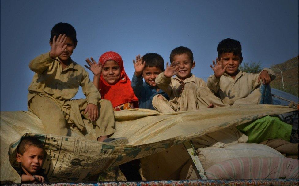 In this photograph taken on September 7, 2016, repatriated Afghan refugee children wave from a packed vehicle preparing to cross the border into Afghanistan, at the Torkham crossing point in Pakistan's tribal Khyber district.