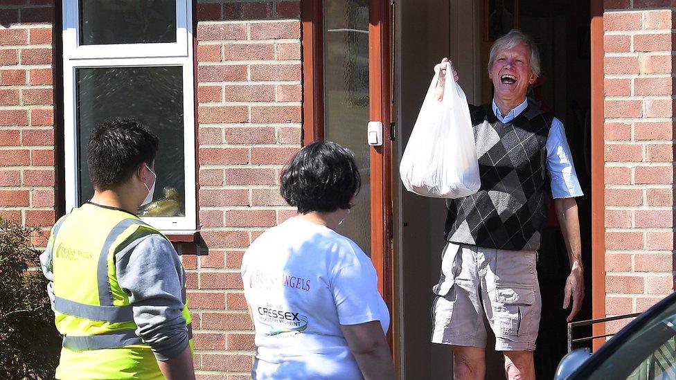 A man receives a shopping bag from mutual aid workers