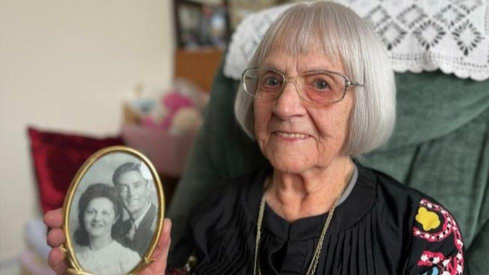 Grace Greenaway, holding a picture of herself and her husband Eirc