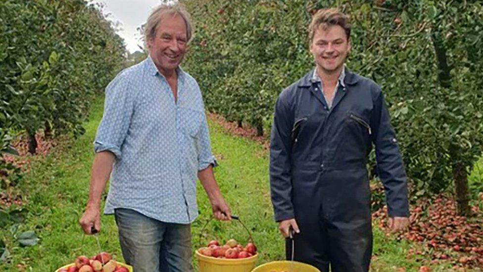 Giles and Rollo wood carrying a bucket of apples through their orchard