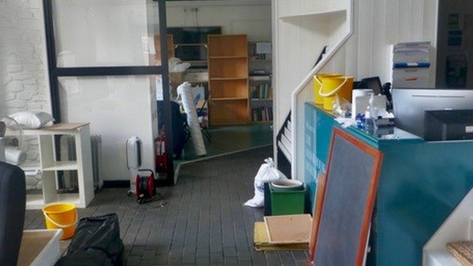 Part of the library building showing buckets, heaters and items removed from the wall and shelves