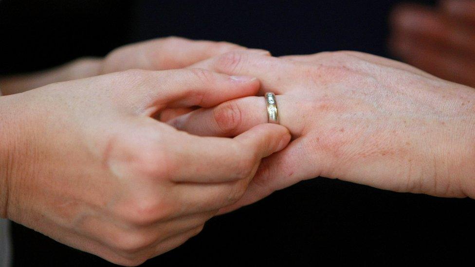 A gay couple exchanging wedding rings