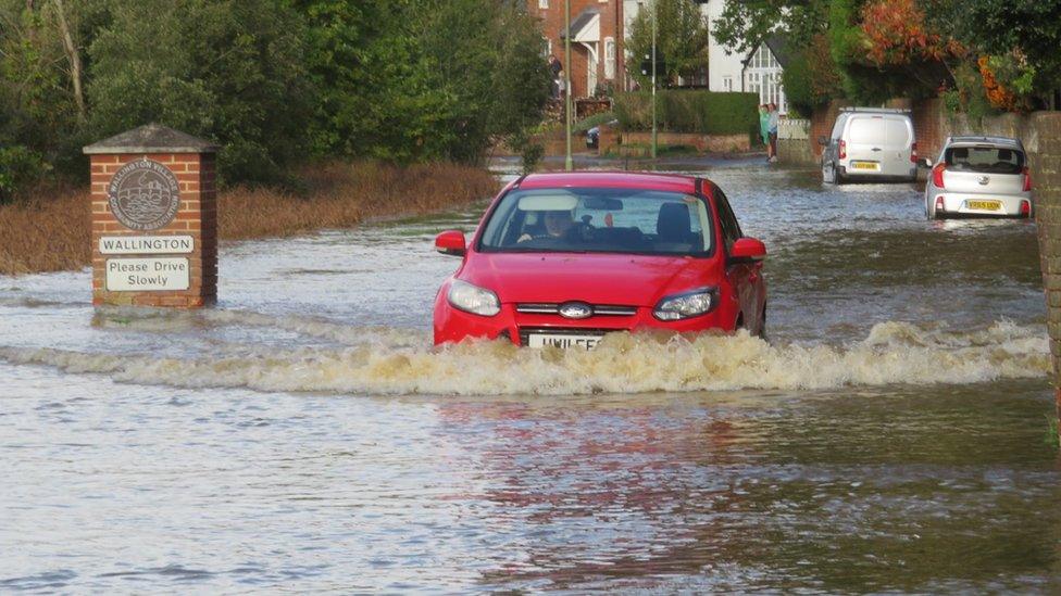 Red car driving through floodwater