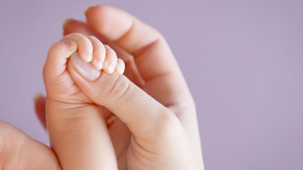 Baby holding mother's hand