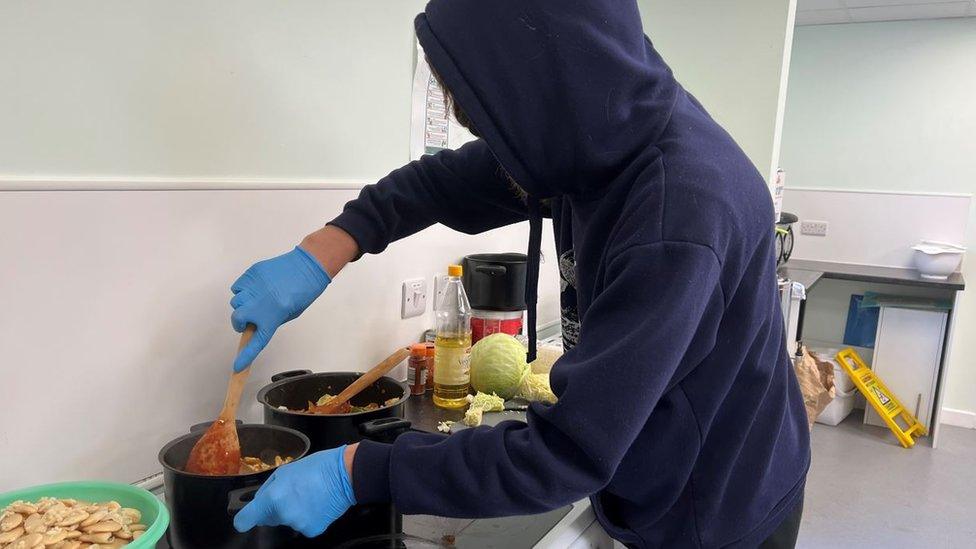 Two Saints kitchen visitor cooks food