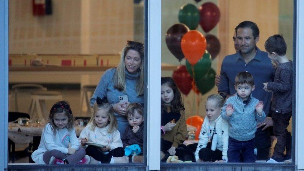 People watch the parade from a window