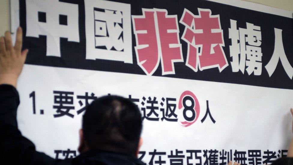 Workers paste a sign reading "China illegally abducts Taiwanese people" during a press conference organized by lawmakers from the Democratic Progressive Party (DPP) at Parliament in Taipei on April 12, 2016