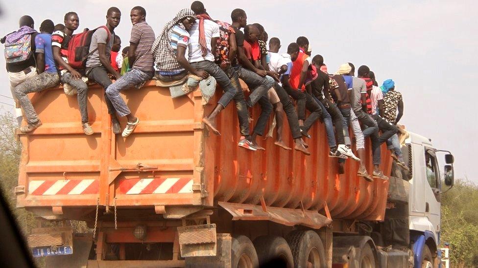 Men sitting on top of a lorry