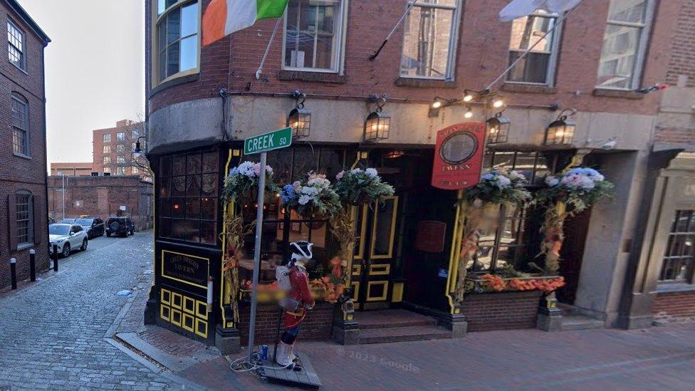 American pub in a narrow street with hanging baskets on its walls