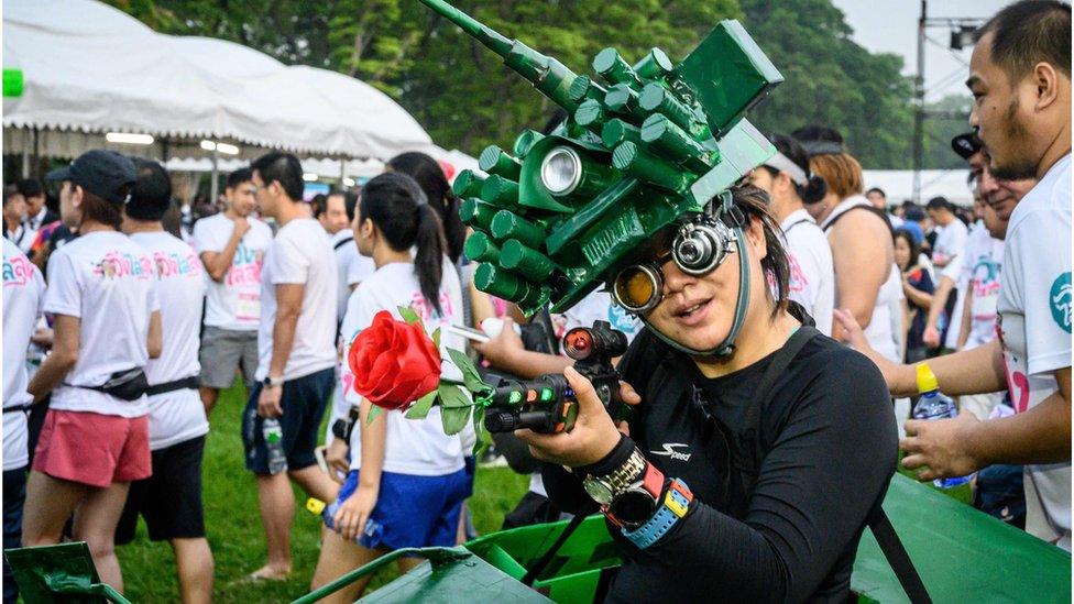 A woman in a tank costume poses before a "run against dictatorship" in Bangkok