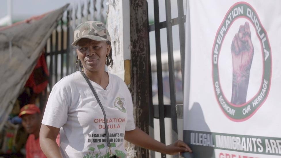 Dimakatso Makoena in front of an Operation Dudula banner on the outskirts of Johanesburg, South Africa