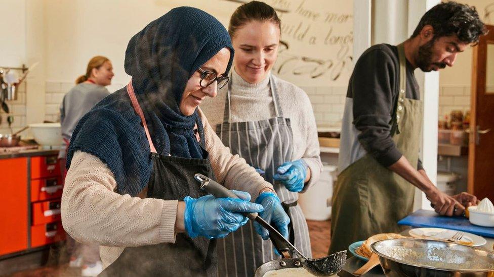 Three people cooking in a large kitchen