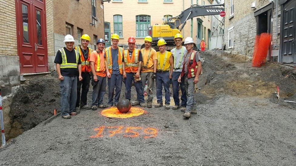 Workers pose beside the cannonball in Quebec