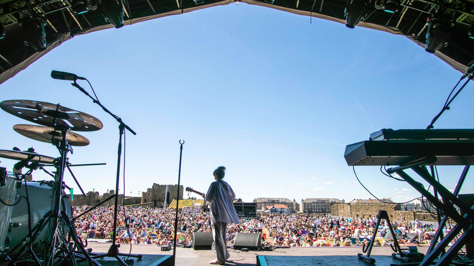 A woman with her back to the camera looks out over a crowd of people