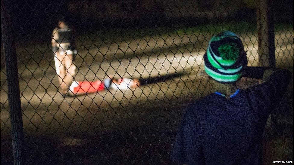 A young boy looks at a man lying in a parking lot with what appears to be gunshot wounds. 9 August 2015 in Ferguson, Missouri.