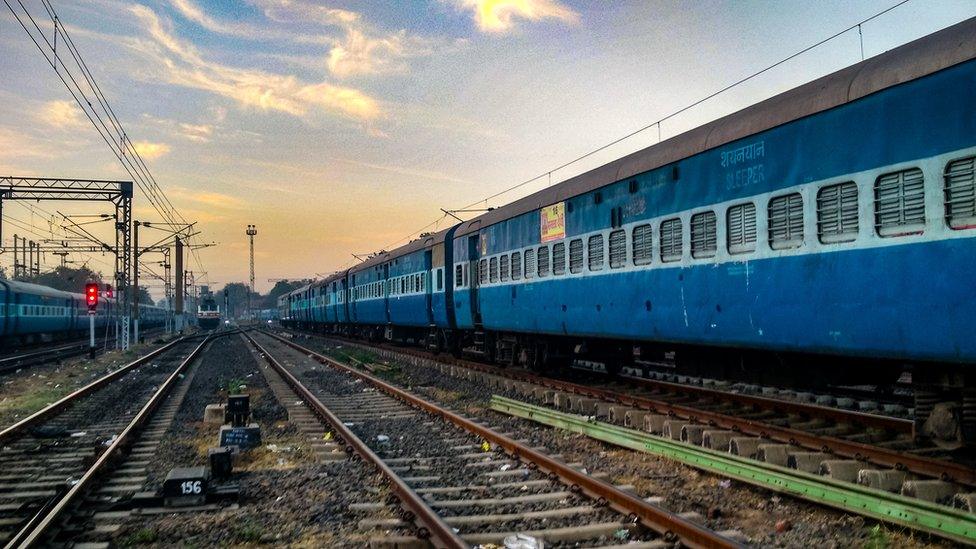 Train On Railroad Track Against Sky During Sunset - stock photo