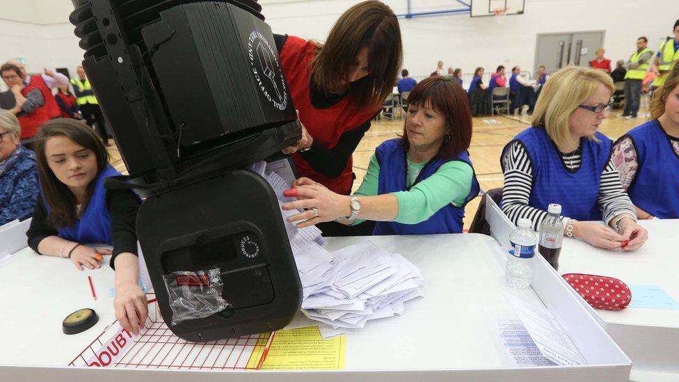 Electoral staff empty a ballot box for counting