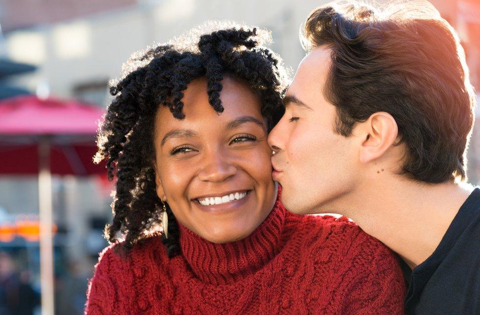 Man kissing woman on cheek