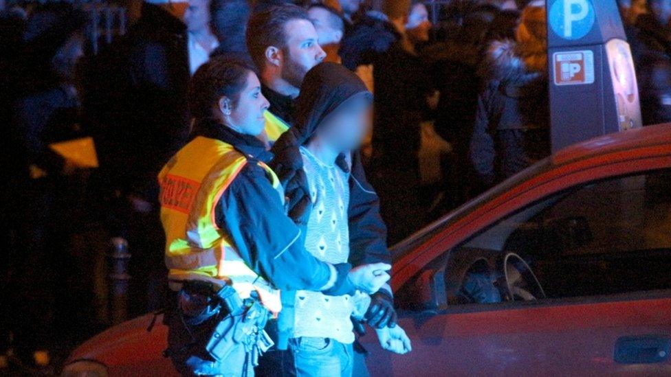 Picture taken on 1 January 2016 shows police arresting a man as people gather in front of the main railway station in Cologne, western Germany