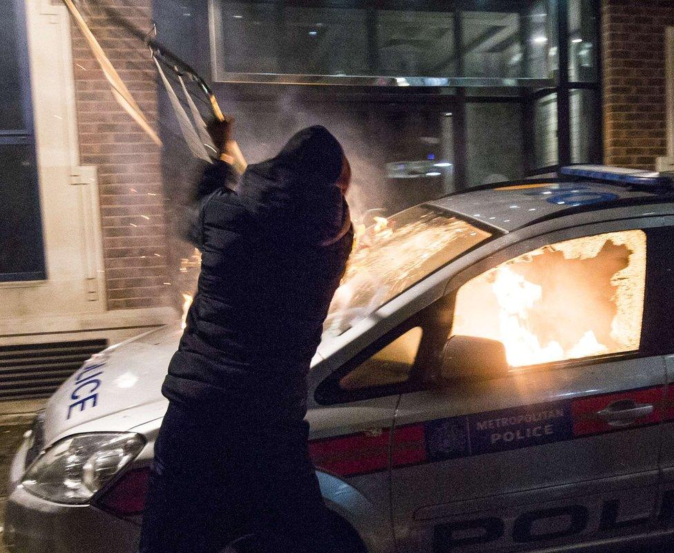 A protester attacks a parked police car