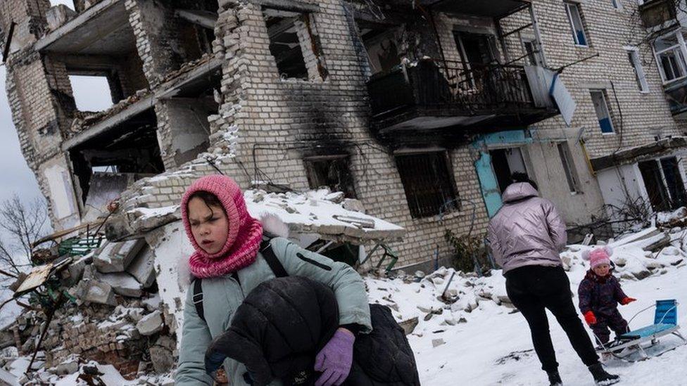 Family outside destroyed building in Izyum