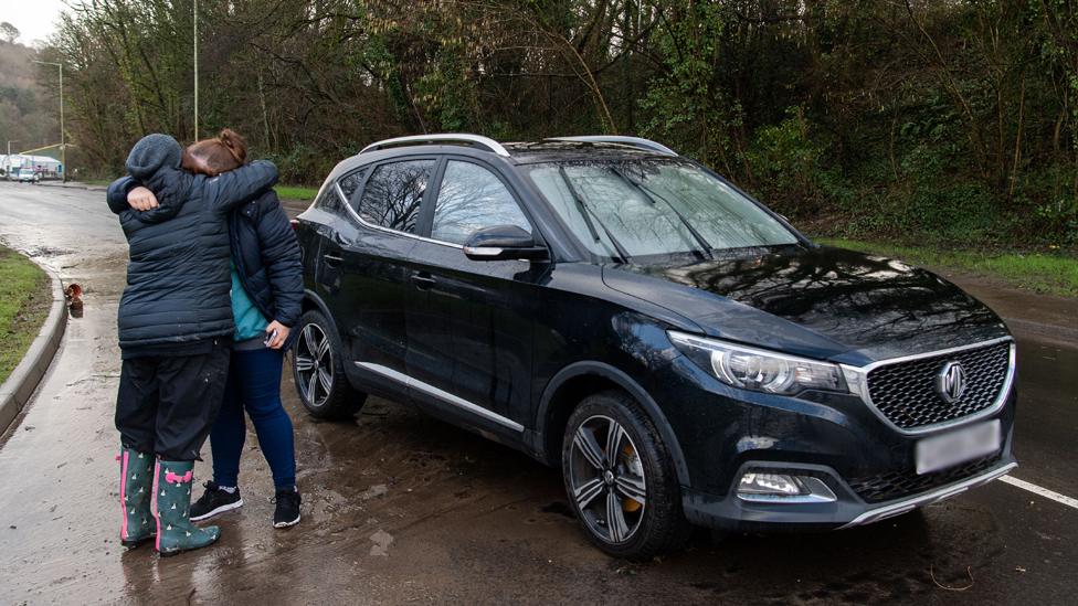 A woman embraces a relative - her new car was found 250m away after floating down a flooded street in Nantgarw