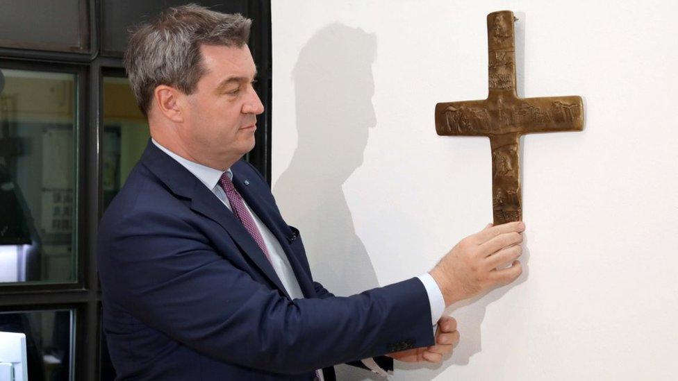 Bavaria's Premier Markus Söder places a cross in the lobby of the state chancellery in Munich